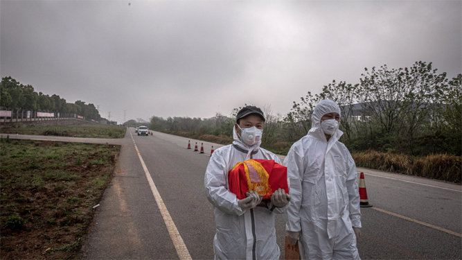 Un hombre porta una urna funeraria con los restos de una víctima de la pandemia en la provincia de Wuhan.
