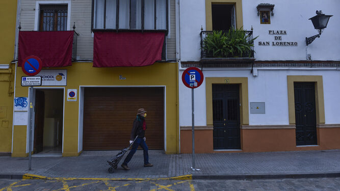 Un peatón con mascarilla y carro de la compra recorre una desértica Plaza de San Lorenzo