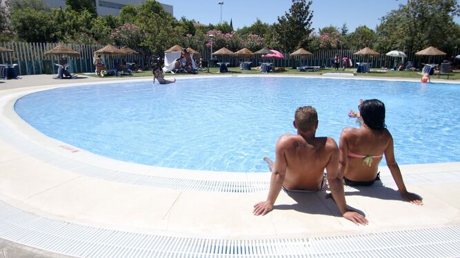 Dos jóvenes sentados en el borde de una piscina.