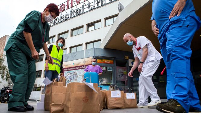 Varios sanitarios del hospital de Bellvitge (Barcelona) recogen las bolsas de comida entregadas por los voluntarios de la ONG Acción Planetaria.