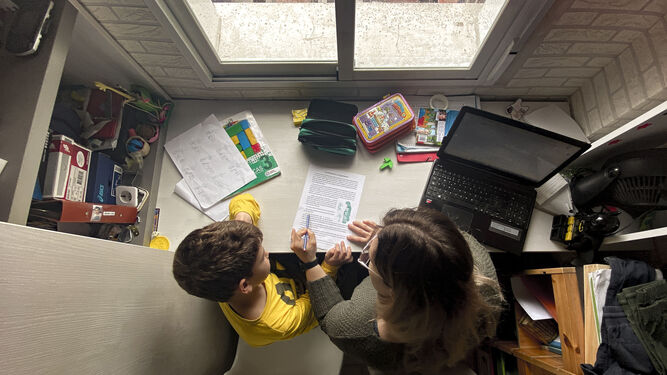 Un niño sigue en casa sus clases, con la ayuda de su madre y conectado a internet.