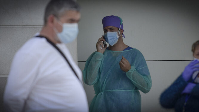Un profesional atiende una llamada de teléfono a las puertas de un centro sanitario.