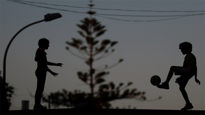 Dos niños juegan a la pelota al atardecer en Godella (Valencia) durante el tercer día de apertura para los menores de 14 años.