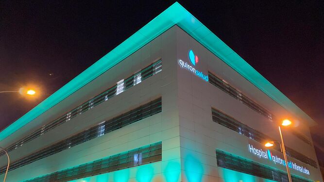 El Hospital Quirónsalud Infanta Luisa con su fachada iluminada de color verde esperanza.