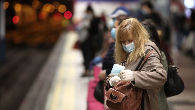 Una mujer con mascarilla en un andén de la estación de metro