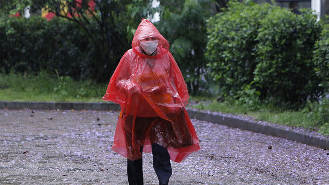 Un hombre se resguarda de la lluvia con un impermeable.