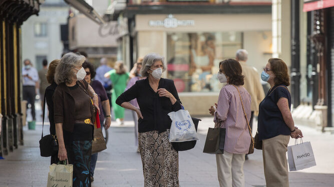 Varias mujeres, con mascarillas, en una calle de Sevilla.