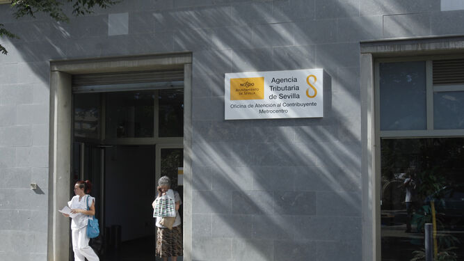 Dos personas en la entrada principal de la Agencia Tributaria de Sevilla.