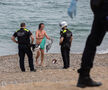 Dos agentes de la Guardia Urbana de Barcelona hablan con un joven que se acaba de bañar en la playa estando prohibido.