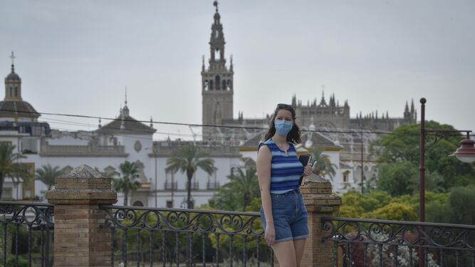 Una joven pasea por Sevilla, con la Giralda de fondo.