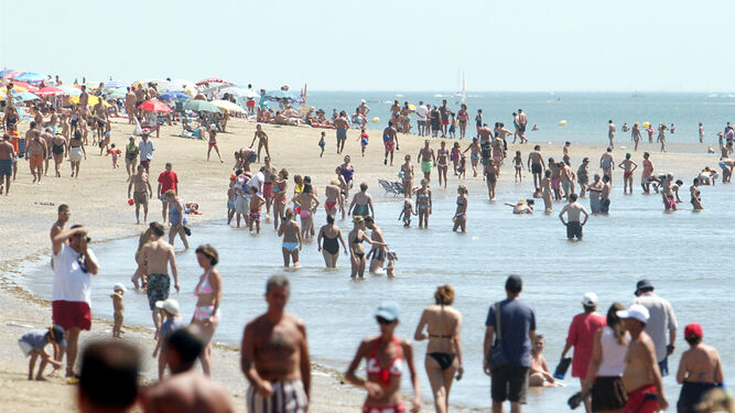 Decenas de bañistas paseando por la orilla de la playa de isla Canela, en Ayamonte.