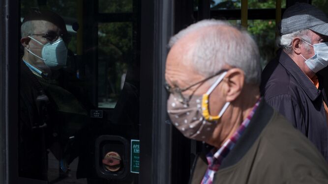 Varios ancianos  protegidos con mascarillas  se suben y bajan de un autobús en Orense.