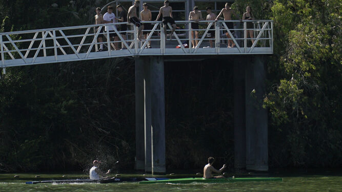Varios jóvenes se concentran en una de las pasarelas sobre el río Guadalquivir.