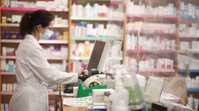 Una dependienta despacha medicinas en una farmacia.