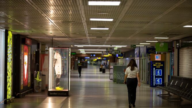 Pasillo sin vida comercial ni de pasajeros de acceso a las salas de embarque en el aeropuerto de Sevilla, esta mañana. A partir del 1 de julio abren algunas zonas de restauración y venta.