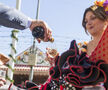 Un hombre vestido de corto sirve manzanilla  a una mujer con traje de flamenca en un carruaje en la Feria de abril de Sevilla