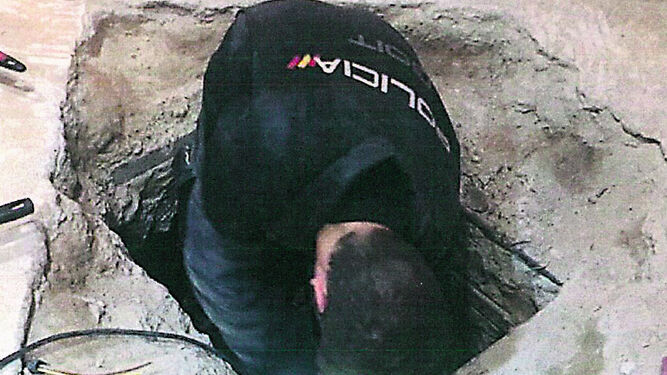 Un agente en la excavación realizada en la fosa séptica donde fueron hallados los cadáveres.