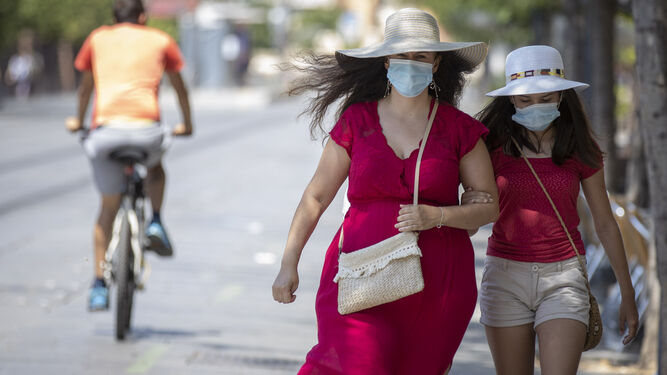 Una mujer camina junto a una menor ataviadas con mascarillas.