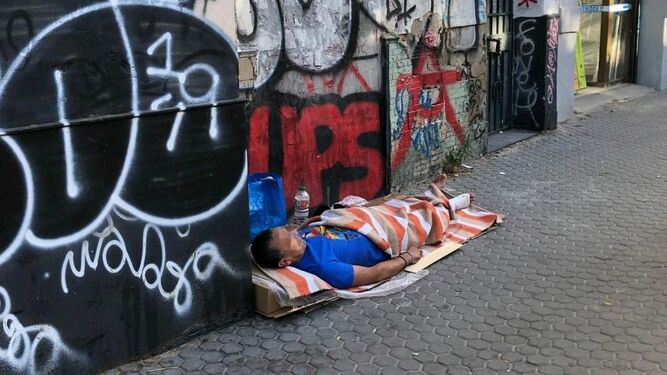 Un indigente duerme en una de las calles del barrio de la Macarena.
