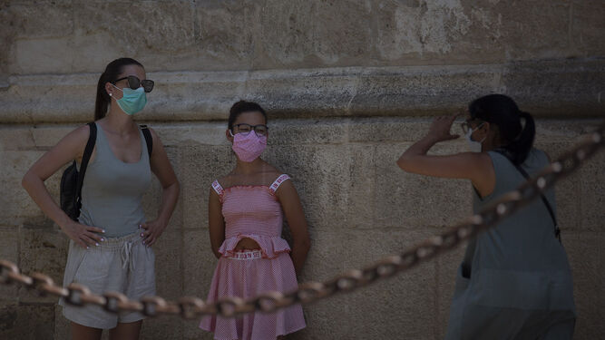 Dos mujeres y una menor se sacan fotografías junto a la Catedral de Sevilla.