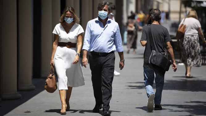 Una pareja camina por una calle de la ciudad haciendo uso de la mascarilla obligatoria.