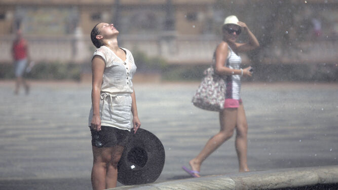Una mujer se refresca en una fuente para tratar de afrontar el calor