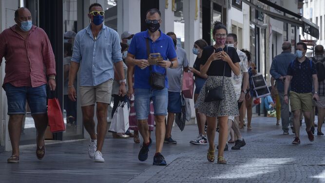 Varias personas, con compras, en el centro de Sevilla.