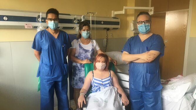 La paciente recientemente intervenida junto a un familiar y los dos cirujanos de la sección de vascular del servicio de Neurocirugía del Virgen del Rocío que han realizado la operación.