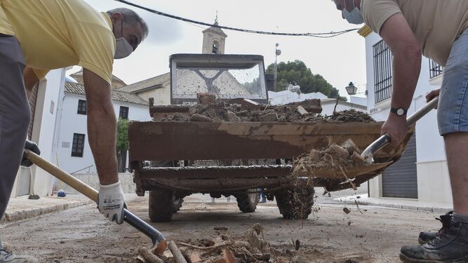 Dos operarios retiran escombros de una calle de Estepa.