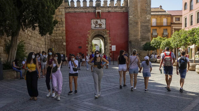 Grupos de turistas pasean por el entorno monumental de Sevilla en agosto.