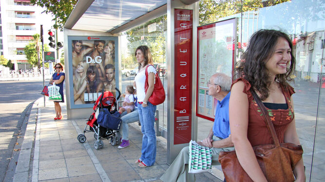 Varios usuarios de Tussam aguarda al autobús en las marquesinas de la plaza Duquesa Cayetana de Alba.