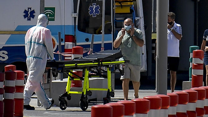 Un sanitario traslada una camilla en el exterior de un centro hospitalario de Granada.