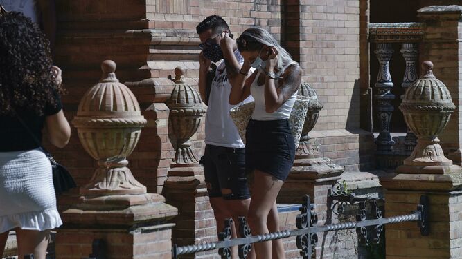 Dos jóvenes se ajustan sus mascarillas, ayer en la Plaza de España.