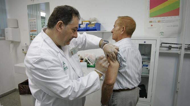 Un médico administra la vacuna de la gripe estacional a un hombre en un centro de salud.
