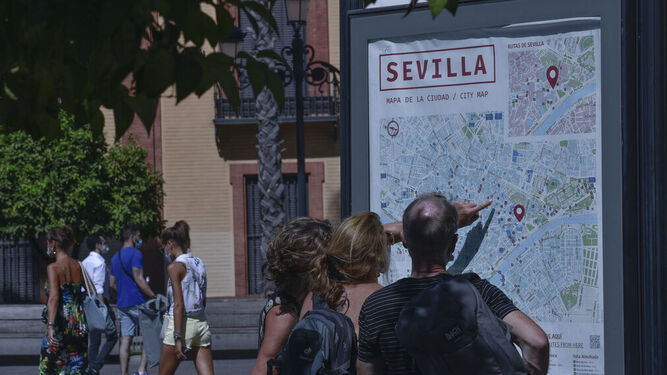 Turistas consultan un plano de Sevilla bajo el sol.
