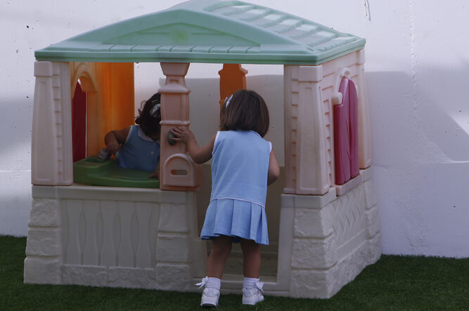 Dos niñas disfrutan de una casa de plástica instalada en el patio de la escuela infantil Chicle.