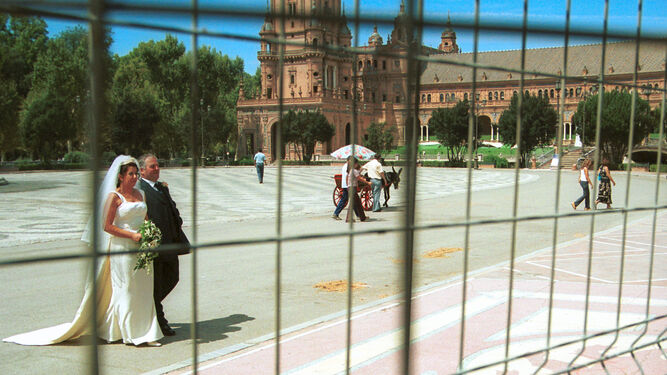 Una pareja recién casada pasea por la Plaza de España de Sevilla.