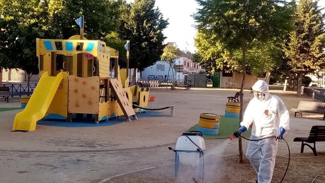 Un operario fumiga un parque infantil en Palomares del Río.