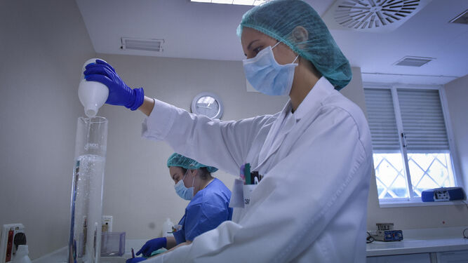 Una sanitaria sostiene dos recipientes con solutos en el laboratorio del Hospital Virgen del Rocío de Sevilla.