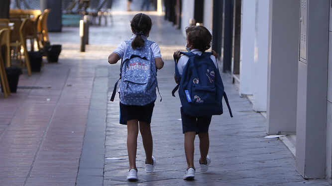 Dos niños caminan juntos hacia el colegio.