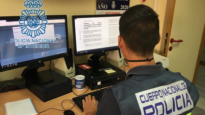 Un agente de la Policía Nacional trabaja con dos ordenadores.