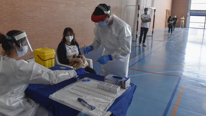 Dos sanitarios preparan muestras en Écija mientras una vecina espera su turno.