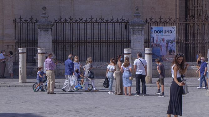 Varias personas pasean junto a la Catedral de Sevilla.