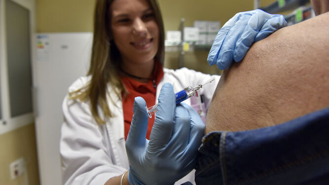 Una enfermera administra la vacuna de la gripe a un paciente.