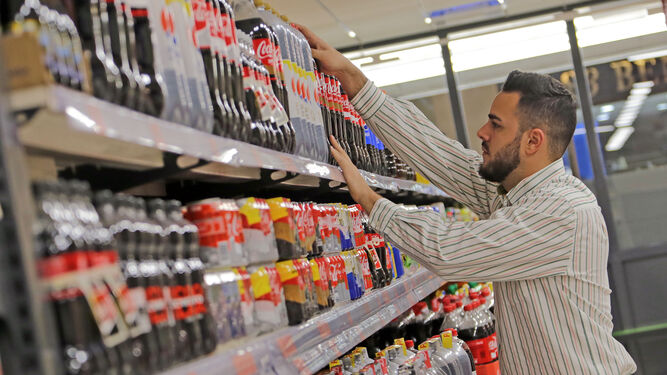 Un trabajador de una cadena de supermercados  repone el lineal  de refrescos.