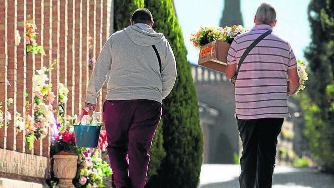 Dos personas pasean por un cementerio en el día de Todos los Santos.