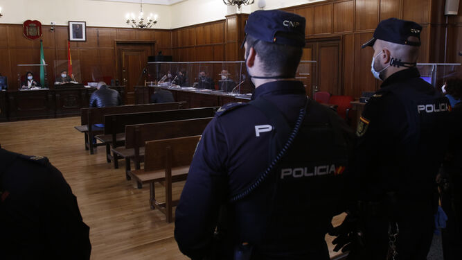 Los dos acusados, sentado en el banquillo y custodiados por la Policía Nacional.