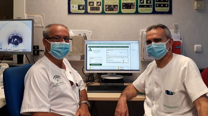 A la izquierda el supervisor de Enfermería del Área de Gestión Sanitaria Sur de Sevilla, Javier Román, acompañado del enfermero Cristóbal Rodríguez cumplimentado la Hoja de Continuidad de Cuidados, en formato digital, dentro de las instalaciones de la resonancia magnética.