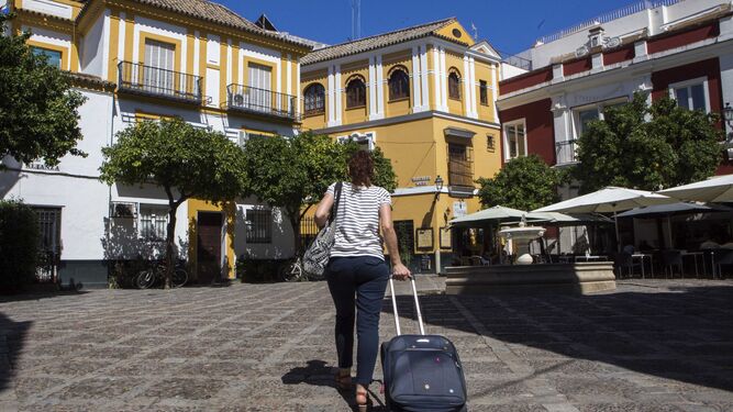Una mujer cruza con una maleta de ruedas la Plaza de la Alianza, en el turístico barrio de Santa Cruz.
