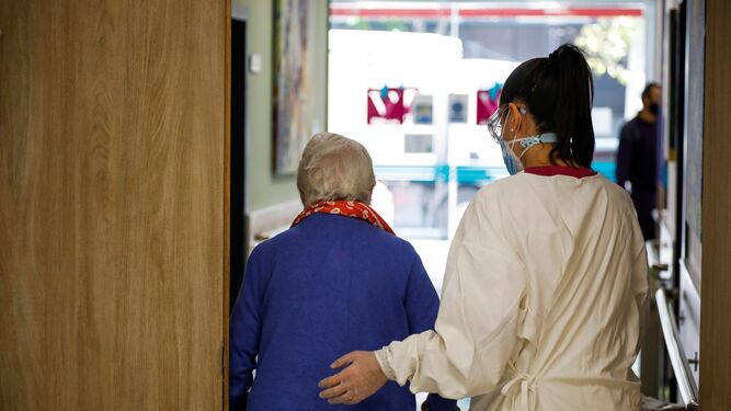 Una sanitaria acompaña a una mujer en un geriátrico.